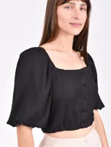 Blusa corta negra con escote cuadrado, mangas abullonadas 3/4 y cierre frontal con botones.