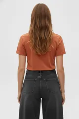 Remera de algodón color verde oliva, de manga corta con puños doblados y cuello redondo. Presenta un pequeño bolsillo en el pecho con un detalle metálico.