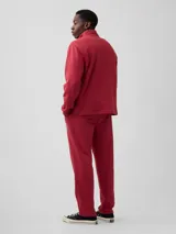 Pantalón deportivo de ajuste holgado color rojo, con bolsillos laterales y elástico en la cintura. Presenta un logo circular estampado en la pierna izquierda.