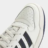 Championes Adidas Forum Low CL de estilo retro inspirado en el básquet. Presentan un diseño en color blanco con detalles en azul marino en las icónicas tres tiras laterales, el talón y la suela. Están confeccionados con una combinación de cuero y materiales sintéticos, ofreciendo un look clásico y urbano.
