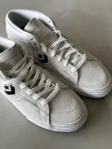 Championes de skate Converse Louie Lopez Pro Mid, color blanco hueso, confeccionados en gamuza con detalles perforados y logo de estrella en negro.