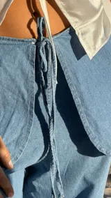 Pantalón de jean celeste con corte amplio y sobrefalda cruzada con lazo.
