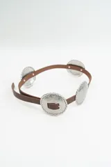 Cinturón de cuero marrón con apliques circulares metálicos plateados de estilo western.