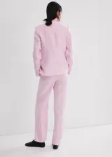 Blazer de lino color rosado, de diseño recto con cuello en pico y solapas con muesca. Cuenta con manga larga, dos bolsillos de ribete delanteros y cierre frontal de un botón.