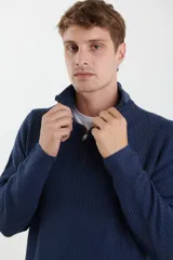 Sweater verde de punto inglés con cuello alto y cierre metálico frontal. Tiene mangas largas y terminaciones en punto canalé.