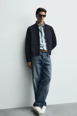 Sobrecamisa de corte regular fit en tejido técnico negro resistente al agua, con cuello estilo bomber en rib elástico, cierre frontal de cremallera y bolsillos plastrón con solapa en la cadera.