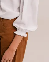 Blusa celeste de cuello mao y mangas abullonadas con puños elásticos. Tiene tajos laterales y botones en la delantera.