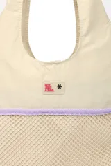 Bolso tipo tote color beige con parte inferior de red y correa larga desmontable.