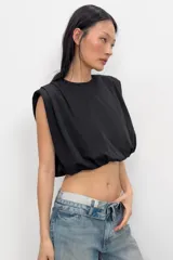 Top de algodón con cuello redondo, diseño sin mangas con hombreras marcadas y detalle de pliegues. Presenta un bajo acabado tipo globo con elástico.