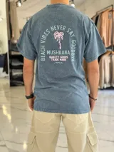 Remera oversize gris con efecto lavado ácido, manga corta y estampa en la espalda con texto y diseño de palmera.