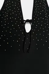 Vestido corto negro con cuello halter, escote pronunciado en pico con lazada central y aplicación de tachas doradas en el área del escote y cuello.