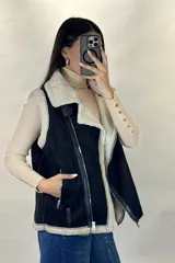 Chaleco tipo gamulán color marrón con interior y bordes de corderito sintético color crema. Presenta cierre frontal y bolsillos laterales con cremalleras metálicas, además de detalles de tiras de cuero sintético.