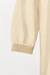 Top de punto fino semitransparente, color beige, con escote redondo y mangas cortas con puños ajustados.