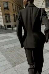 Blazer entallada de color negro con cuello solapa, manga larga y hombreras marcadas. Presenta cierre frontal con dos botones dorados y bolsillos delanteros con solapa.