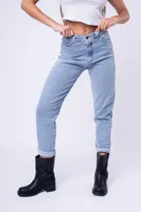 Pantalón de jean estilo mom fit, de tiro alto y corte recto con ruedo doblado. Presenta un lavado claro, cierre frontal con botón y bolsillos laterales y traseros.