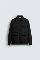 Chaquetón de corte regular fit en color negro, con cuello solapa, manga larga y cierre frontal con botones. Presenta dos bolsillos delanteros de plastrón con solapa en la cadera.
