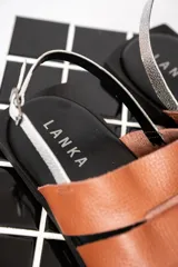 Sandalias chatas color marrón con tiras anchas de cuero y pulsera al tobillo con hebilla metálica.