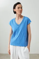 Remera color durazno con cuello en V y detalle de trenza en el escote.