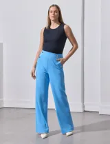 Pantalón naranja de crepe elastizado, corte recto, con bolsillos delanteros y apliques de botones metálicos.