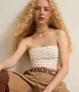 Blusa cropped sin breteles color blanco con pequeños apliques dorados.