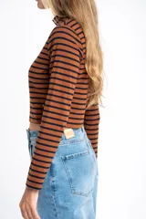 Polera de manga larga, corte ajustado al cuerpo, con cuello alto. Presenta un estampado de rayas horizontales en tonos marrón camel y azul marino.