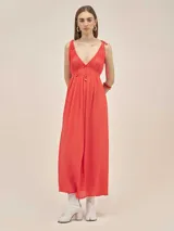 Vestido largo de crepe con breteles ajustables mediante lazos en los hombros. Presenta un escote profundo con tiras frontales para anudar y terminaciones metálicas en cobre. Diseño fluido y ligero.