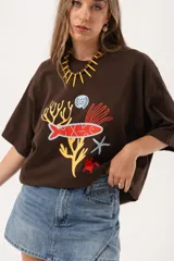 Remerón oversize de algodón color chocolate con estampado de motivos marinos en tonos rojo, amarillo, azul y blanco.