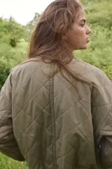 Campera bomber acolchada en tejido guateado color verde militar. Modelo oversized con cuello corto acanalado, hombros caídos, cierre con botones a presión y bolsillos delanteros de parche. Puños y bajo acanalado. Forrada.