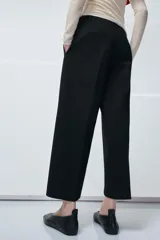 Pantalón de tiro medio confeccionado en viscosa, con diseño de corte recto y largo tobillero. Presenta cintura con trabillas, bolsillos laterales y bolsillos de vivo en la parte posterior. Cierre frontal con cremallera, botón y ganchos metálicos.