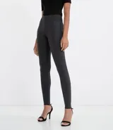 Pantalón tipo legging de tiro alto, color gris oscuro, con paneles laterales elásticos en la cintura y costuras verticales que estilizan la silueta.