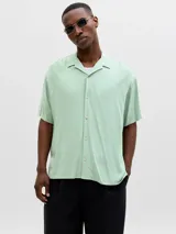 Camisa de manga corta color verde menta, con cuello cubano y cierre frontal con botones.
