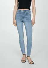 Jeans de tiro alto y corte skinny, confeccionados en tejido de algodón con elástico. Presentan diseño clásico de cinco bolsillos, trabillas para cinturón y cierre frontal con cremallera y botón.