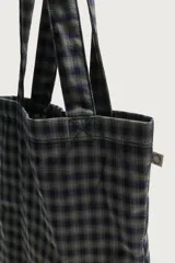 Bolso tipo shopper de la colección Benito Antonio x Zara, confeccionado en tejido con estampado a cuadros en tonos marrones y blancos. Cuenta con compartimento principal sin cierre, doble asa de mano y un pequeño bordado distintivo en la parte inferior.