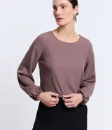 Blusa de crepé color lila, con escote redondo y mangas largas con puños elásticos.