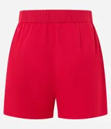 Short rojo de sastrería con pliegues delanteros, trabillas en la cintura, cierre por botón y cremallera, y bolsillos laterales tipo cuchillo.