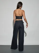 Jean azul oscuro de corte wide leg y tiro alto, con costuras pespunteadas verticales al frente y cinturón incorporado con hebilla cuadrada.