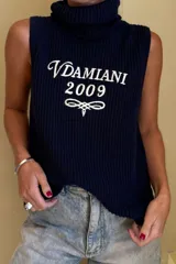 Chaleco tejido de punto en color azul marino, con cuello alto y diseño sin mangas. Presenta un bordado frontal en color blanco con el texto Vdamiani 2009 y un detalle ornamental.