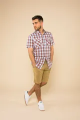 Camisa de manga corta con estampado de cuadros en tonos verdes, azules y blancos. Presenta cuello clásico, cierre frontal con botones y dos bolsillos delanteros con solapa.