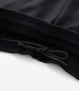 Pantalón deportivo de corte slim para hombre, confeccionado en poliéster color negro. Presenta cintura elástica con cordón de ajuste, bolsillos laterales y diseño ajustado en muslos y rodillas.