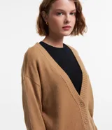 Cardigan corto de punto color marrón, con cuello en V, manga larga y cierre frontal con botones. Presenta puños y bajo acanalados.