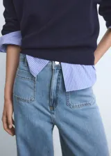 Pantalón de jean estilo denim con corte de pierna ancha y cintura alta. Presenta dos bolsillos de parche en la parte delantera, dos bolsillos traseros, trabillas para cinturón y cierre frontal con botón y cremallera.
