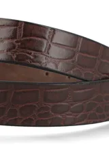 Cinturón de cuero natural con textura efecto cocodrilo en color cognac. Presenta una hebilla metálica de diseño cuadrado en color dorado y pasador de cuero.