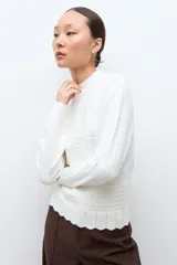 Sweater de punto color crudo con cuello alto tipo media polera, manga larga y diseño con textura de líneas horizontales. Presenta un borde inferior con terminación ondulada.