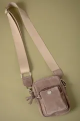 Bolso tipo pocket bag confeccionado en cuero vacuno, con bolsillo frontal con cierre y correa de cinta regulable. Forrado en tela de algodón.