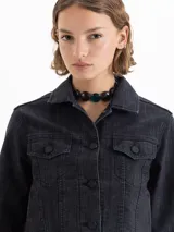 Campera de denim color negro, de silueta clásica y fit estándar, con leve elasticidad. Tiene cuello camisero, botones frontales y bolsillos con solapa en el pecho.