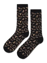 Medias largas de algodón color negro con estampado de motivos western en color beige, incluyendo botas, revólveres, herraduras y cráneos de toro.