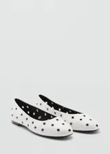 Zapato tipo bailarina color blanco con diseño troquelado de ojales metálicos, punta redonda y suela plana.