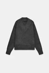 Jersey de punto color gris oscuro, con cuello pico y manga larga. Los acabados son en rib.