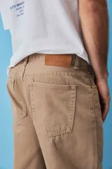Pantalón de jean estilo baggy, de corte holgado y tiro medio, en color beige tostado, con diseño clásico de cinco bolsillos y trabillas para cinto.