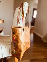 Bolso tote de cuero color marrón con costuras decorativas de hilo de colores.